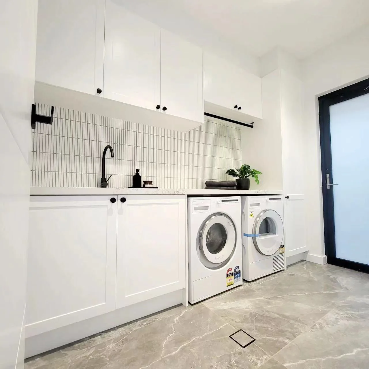 Sleek, modern laundry room featuring premium appliances and elegant cabinetry. Perfect blend of functionality and style.