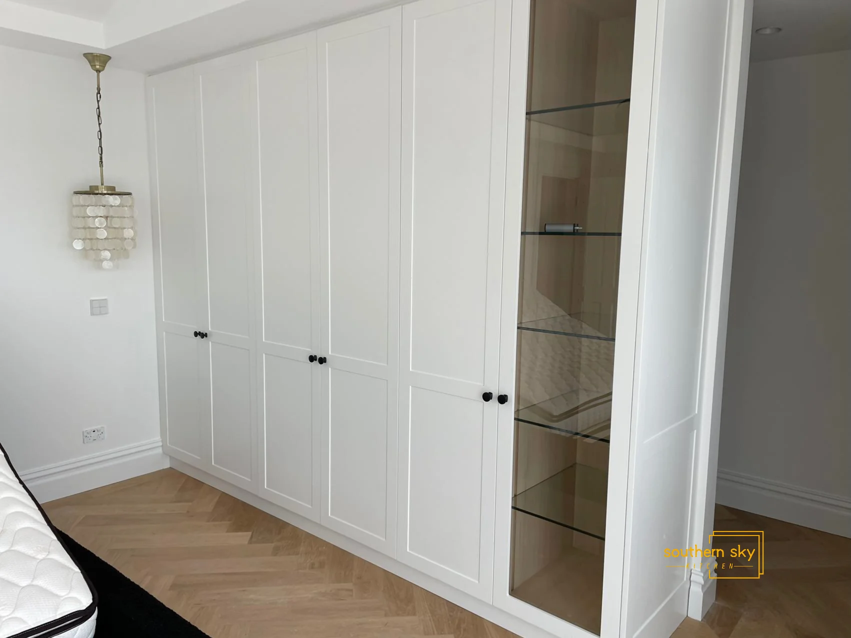 Elegant white wardrobe with glass shelving; showcases expert craftsmanship and modern design, perfect for sophisticated interiors.