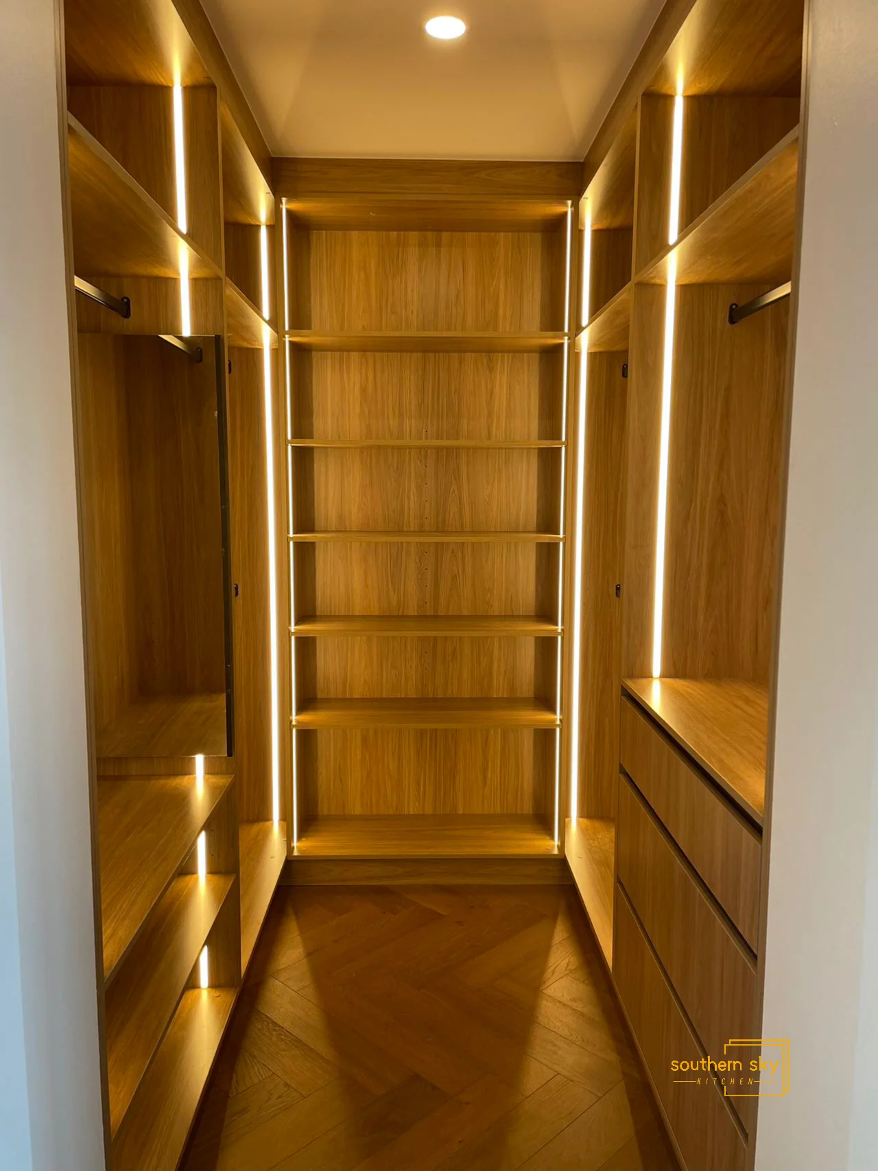Luxurious walk-in closet with sleek wood finish, LED lighting, and exquisite craftsmanship for stylish and functional storage.
