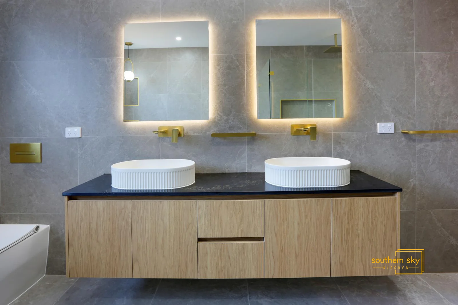Luxurious bathroom design with elegant twin basins, golden fixtures, and ambient LED-lit mirrors, showcasing modern craftsmanship.