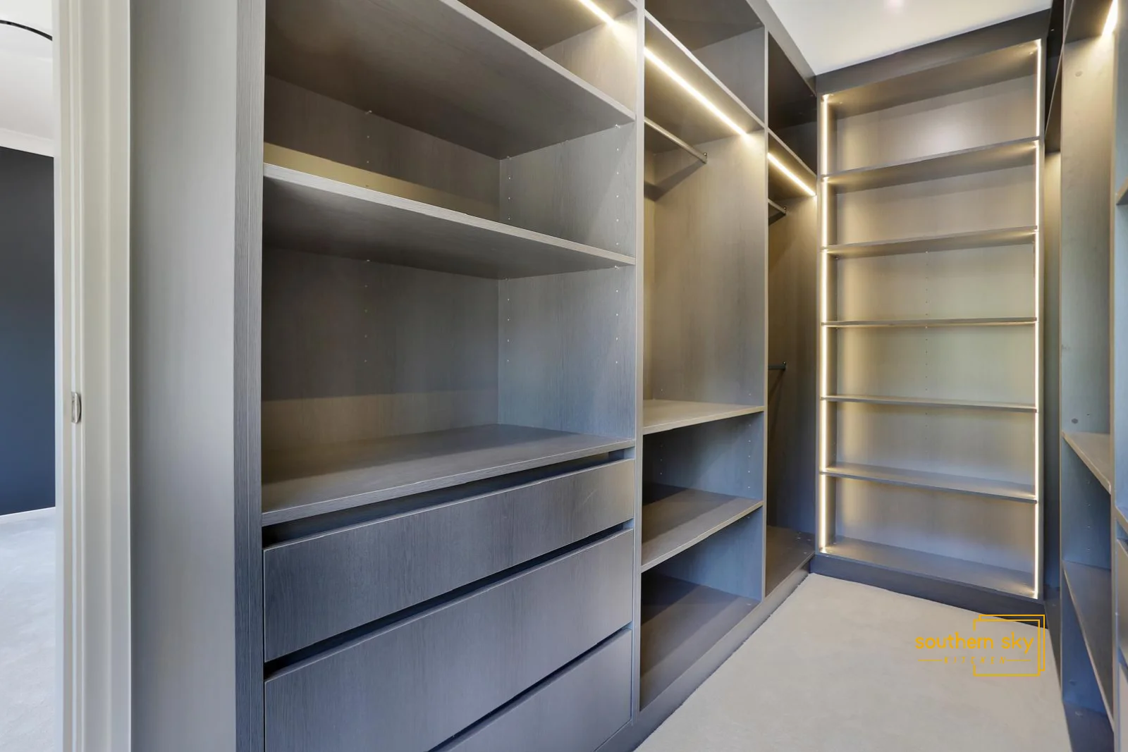 Luxurious walk-in closet with sleek design, impeccable craftsmanship, and modern lighting for ultimate organization.