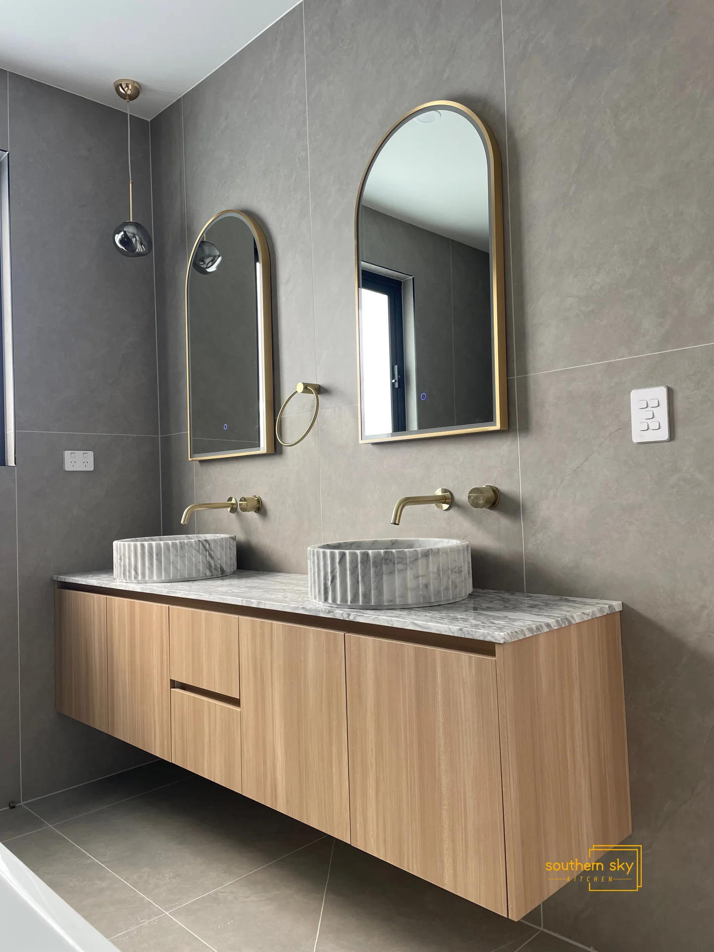 Luxury bathroom design with exquisite marble sinks, elegant wood cabinetry, and modern golden accents for a sophisticated allure.