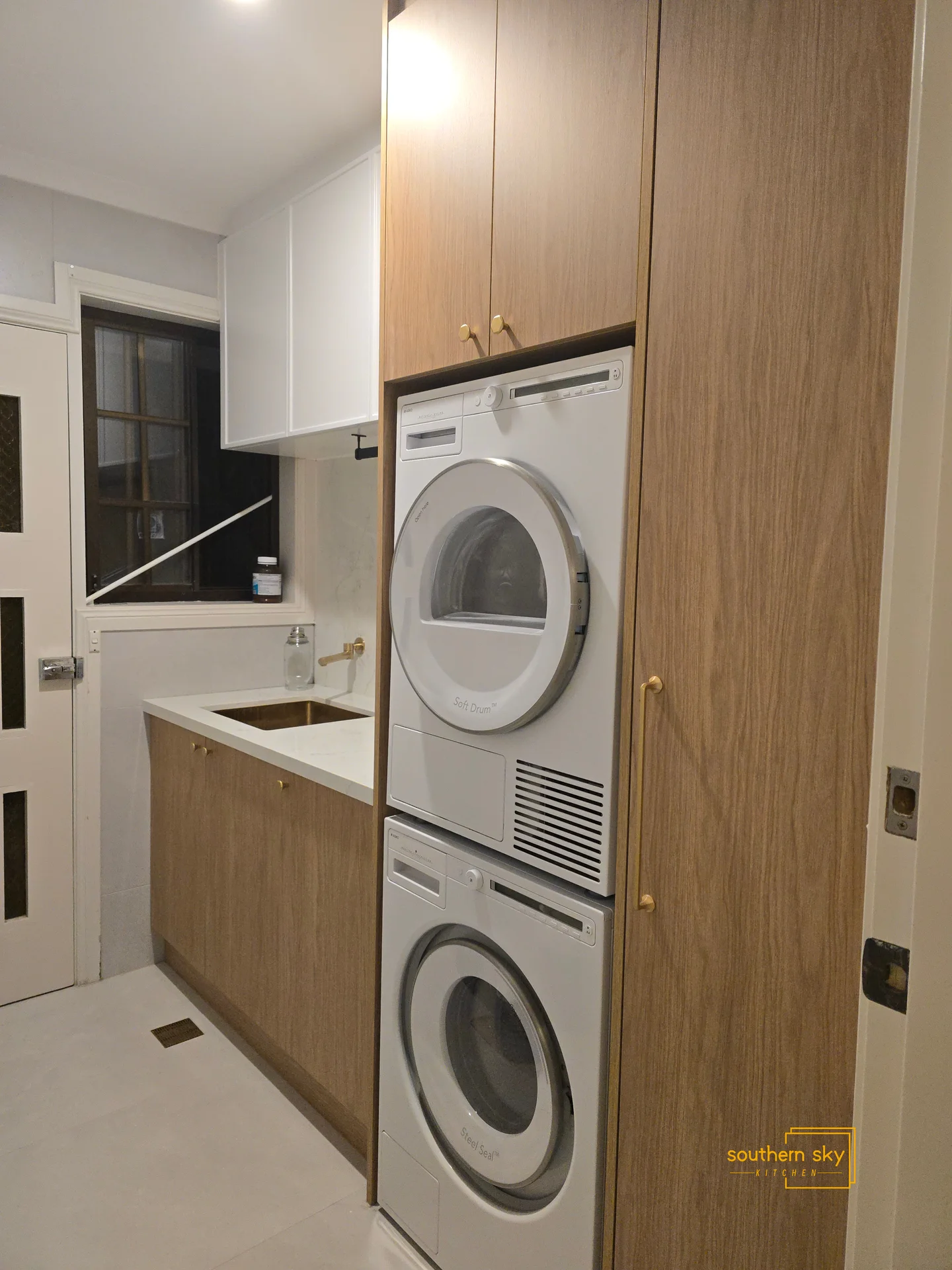 Sleek, modern laundry room with custom cabinetry and high-end appliances; crafted for optimal efficiency and style.