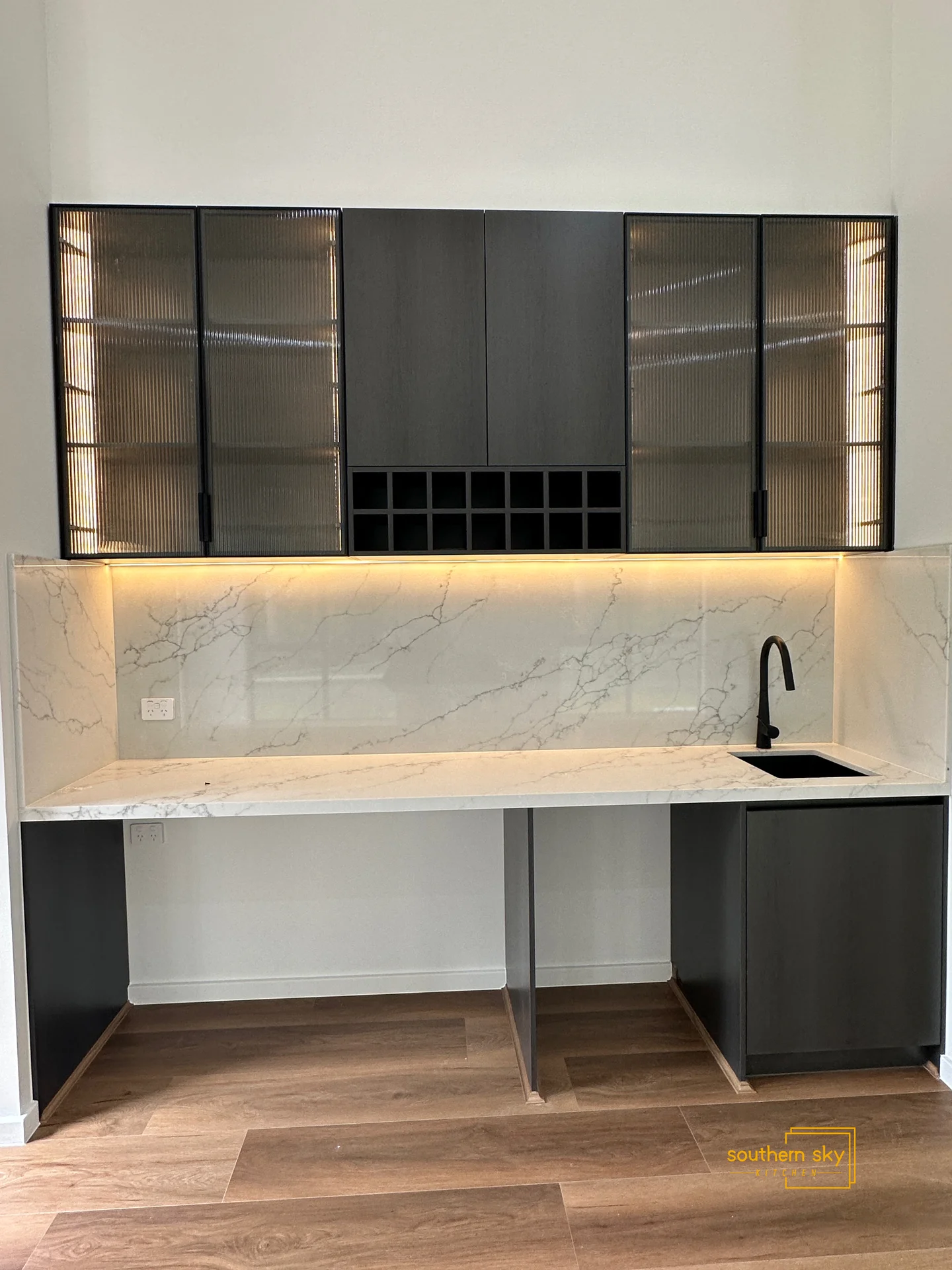 Sleek kitchen cabinetry with elegant marble accents and modern lighting, showcasing premium craftsmanship and design excellence.