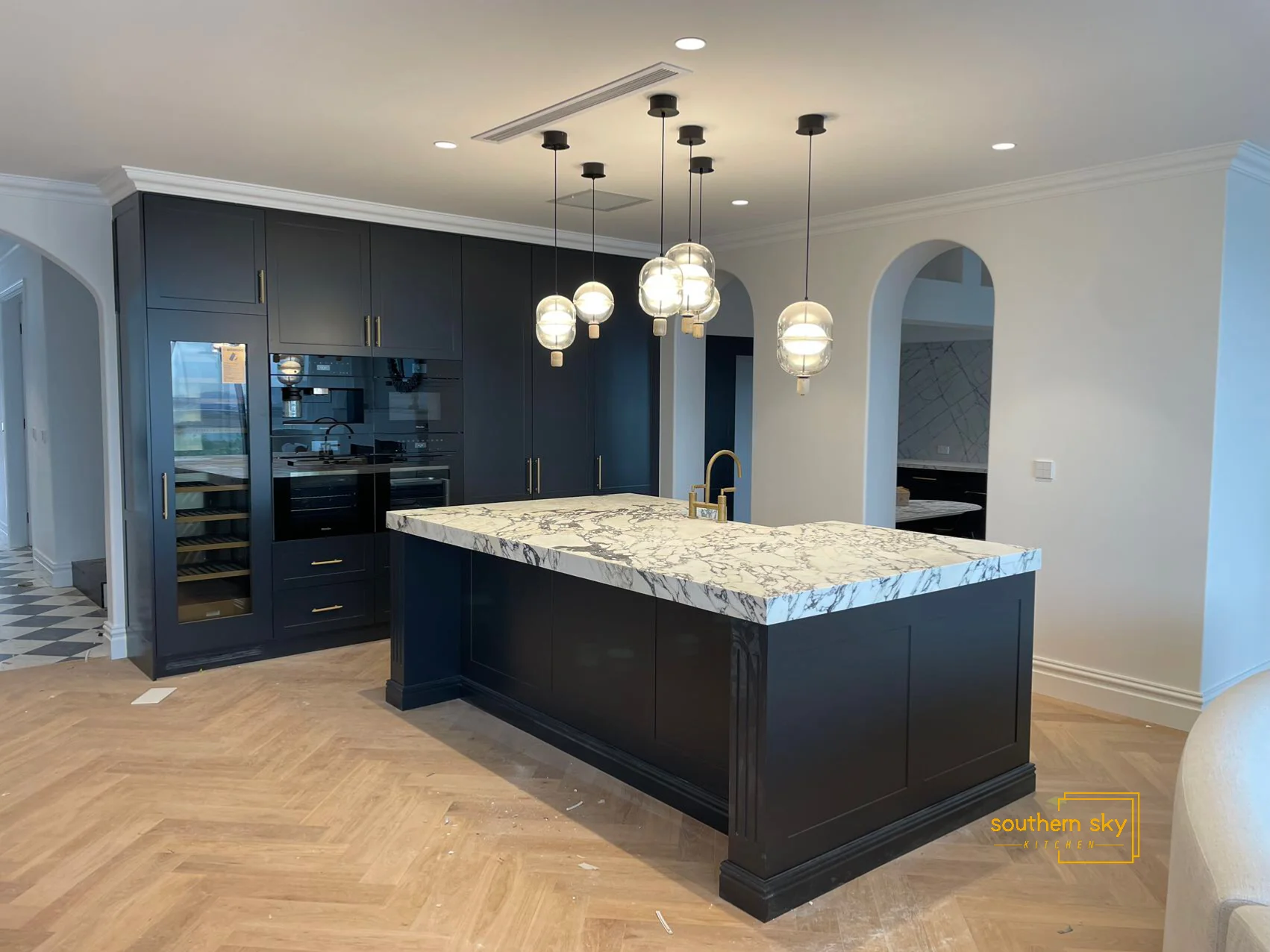 Elegant kitchen island with exquisite marble top, striking pendant lights, and sleek cabinetry. Masterful design and craftsmanship.