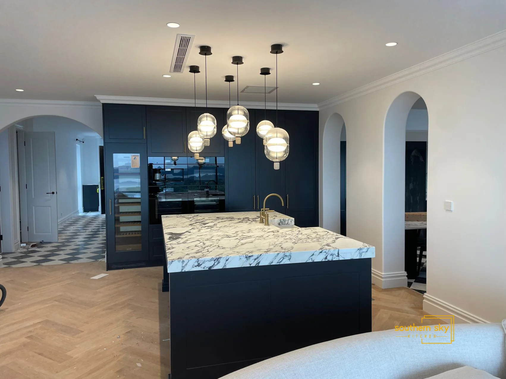 Luxurious kitchen design with marble island and chic lighting, showcasing timeless elegance and superior craftsmanship.