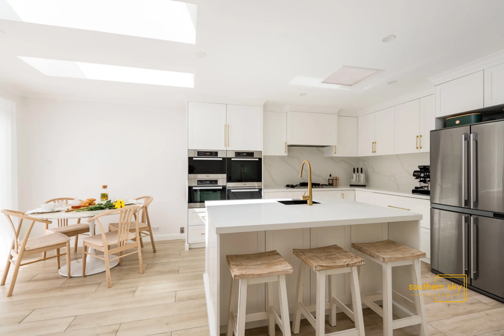 Sleek kitchen design with premium finishes; elegant white cabinetry, modern appliances, and chic wooden accents.