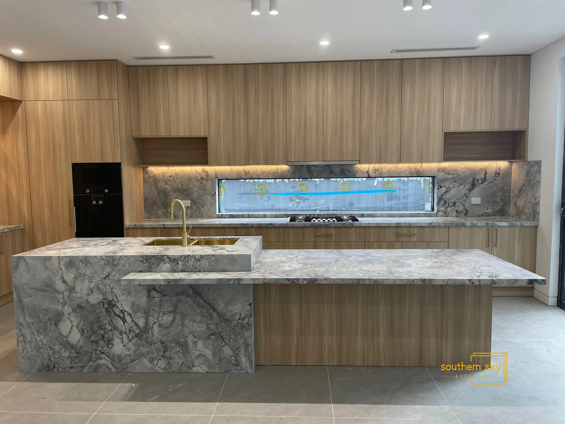 Luxurious kitchen with elegant marble countertops and modern wood cabinetry, showcasing exquisite craftsmanship and sleek design.