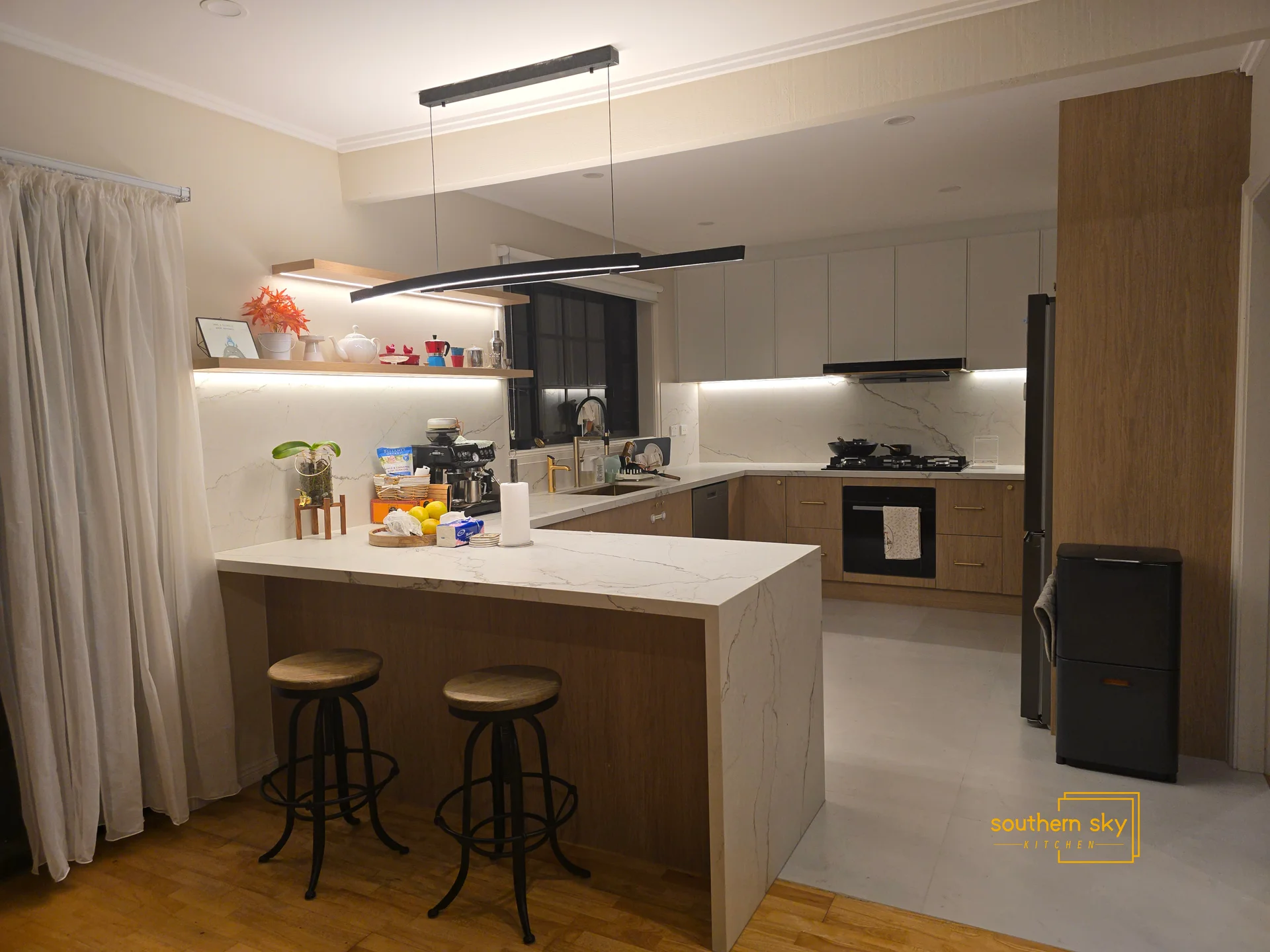 Modern kitchen with impeccable craftsmanship and sleek design; elegant marble surfaces and chic lighting perfect for any home.