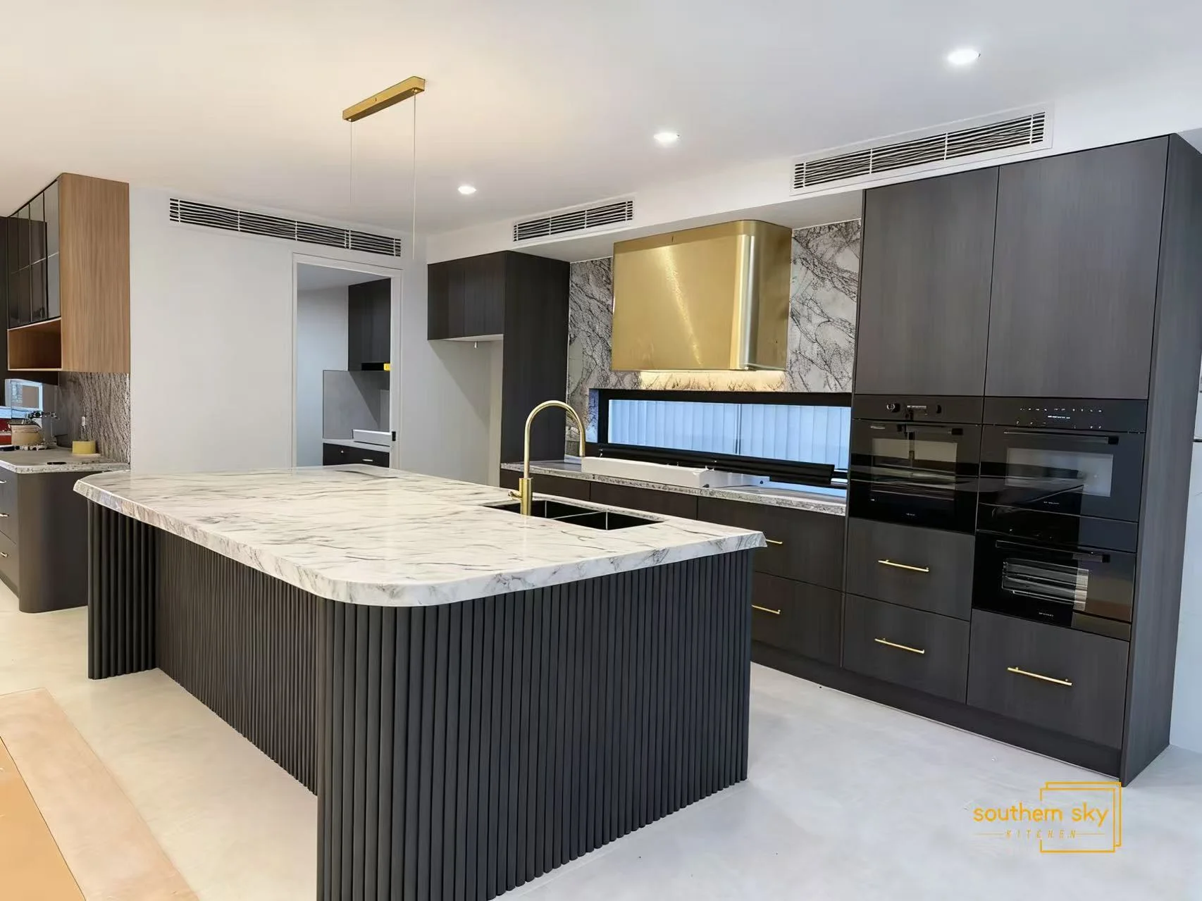 Luxury kitchen with exquisite marble island, sleek cabinetry, and elegant gold accents, showcasing superior craftsmanship.