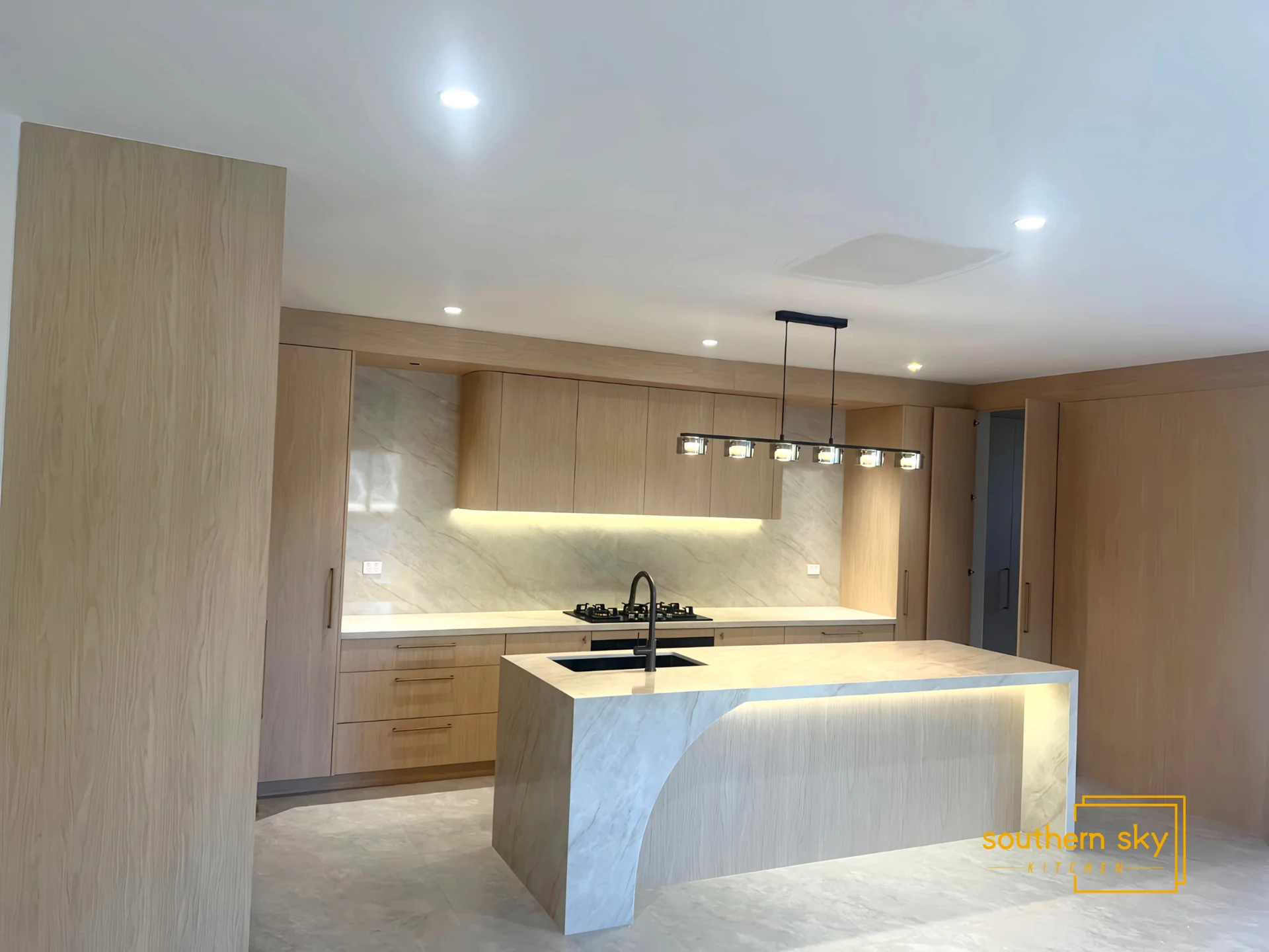 Sleek modern kitchen with premium wood finishes and elegant stone countertops, showcasing masterful design and craftsmanship.